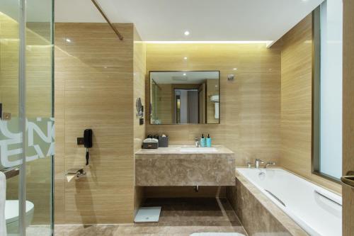 a bathroom with a sink and a tub and a mirror at Novotel Wuxi in Wuxi