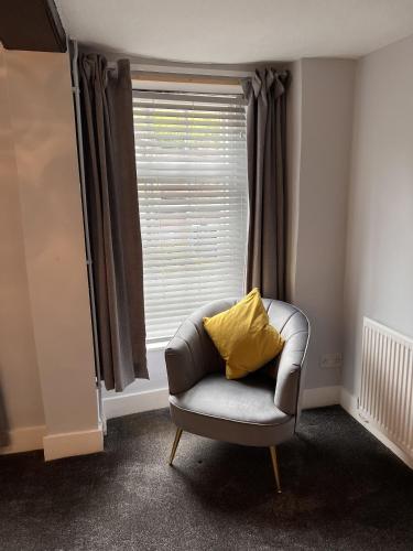 a chair with a yellow pillow sitting in front of a window at The Golden Ball Inn 1728 in Ironbridge