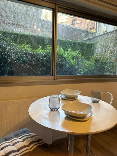 une table blanche avec deux verres et une fenêtre dans l'établissement Superbe Studio Miromesnil Elysée, à Paris