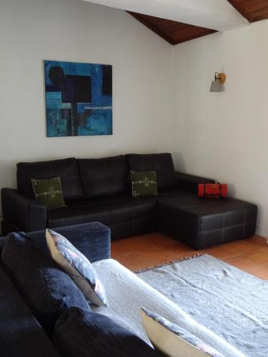 a living room with a black leather couch at New Village in Vila Nova da Baronia