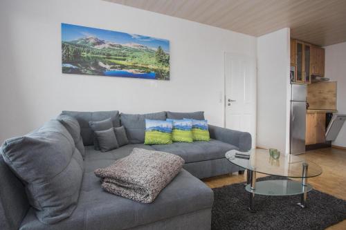 a living room with a gray couch and a glass table at Welcome in - Apartment 59-G 'Leni' direkt an der Piste, mit Balkon, Sauna und Schwimmbad in Winterberg
