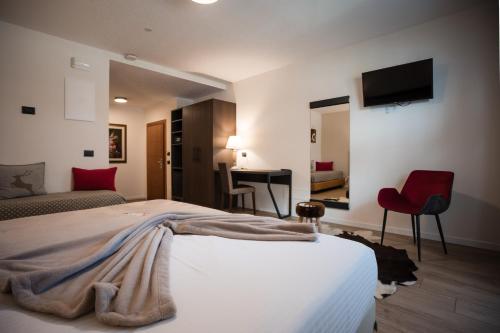 a bedroom with a large bed and a red chair at Olimpia Hotel in Bormio