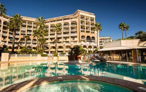 une piscine en face d'un grand bâtiment dans l'établissement Le Cannes Beach 799 - terrasse vue mer panoramique, à Cannes