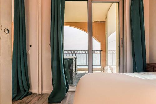 - une chambre avec des rideaux verts et une vue sur un balcon dans l'établissement Le Cannes Beach 799 - terrasse vue mer panoramique, à Cannes