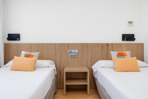 two beds in a room with a table between them at Daniya Alicante in Alicante