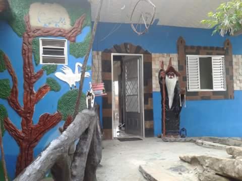 a blue wall with a painting of a house at Casa das Artes in São Thomé das Letras