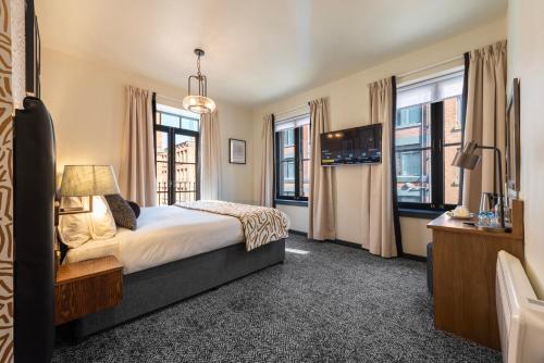 a bedroom with a bed and some windows at Abel Heywood Boutique Hotel in Manchester