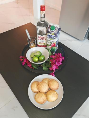 a table with a plate of biscuits and a bottle of whiskey at Villanorée Jacuzzi à Rivière-Pilote in Rivière-Pilote