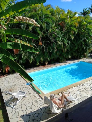 a man laying in a chair next to a swimming pool at La maison in Sainte-Rose