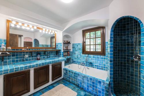 La salle de bains est pourvue de carrelage bleu, d'une baignoire et d'un lavabo. dans l'établissement Magnifique villa avec vue mer panoramique, à Nice
