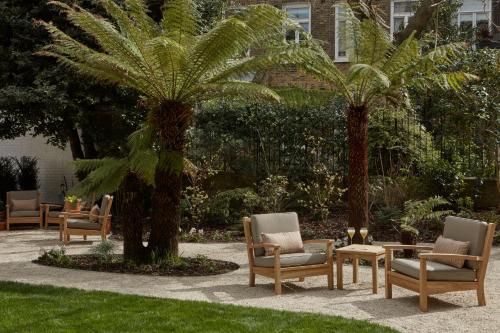 a group of chairs and a palm tree in a yard at Miiro Templeton Garden in London