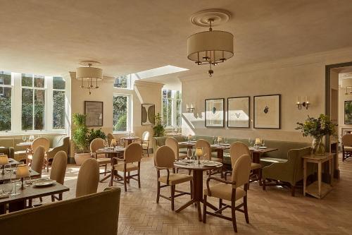 a restaurant with tables and chairs and windows at Miiro Templeton Garden in London