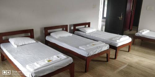 three beds in a room with white sheets at Cheerful two Bedroom Green Villa by Suvana Organics in Lucknow