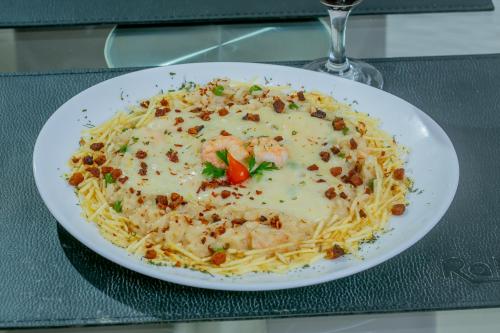 a plate of pasta with shrimp and cheese on a table at Raru's Motel Litoral Norte (Adult Only) in Natal