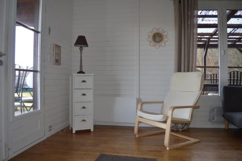 a white chair in a room with a lamp and a dresser at L'Orée du bois in Tenneville