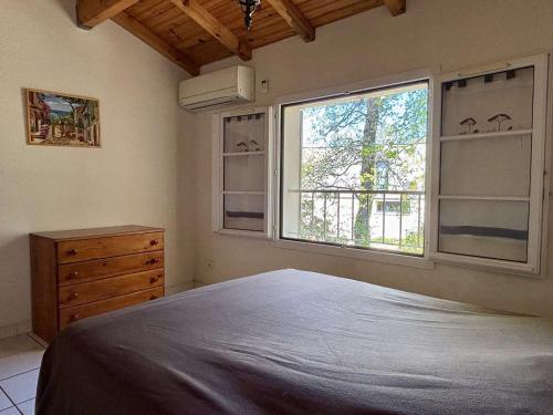 une chambre avec un grand lit et deux fenêtres dans l'établissement Maison avec mezzanine, piscine, parking privé, terrasse et climatisation à 900m de la plage - FR-1-225-695, à Argelès-sur-Mer