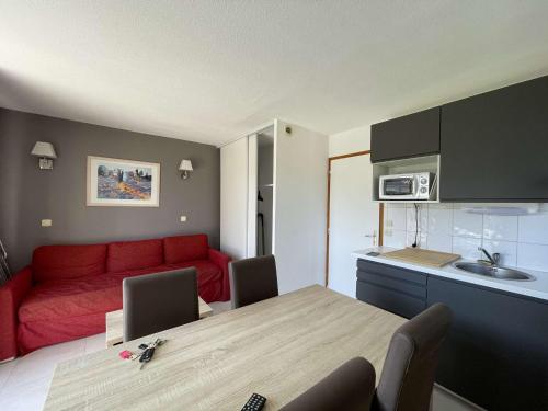 Il comprend une cuisine et un salon avec un canapé rouge. dans l'établissement Maison duplex avec clim, 2 piscines, terrasse, parking, animaux admis - 8 pers. - FR-1-382-165, à Salavas