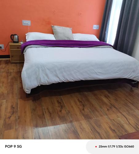 a bedroom with a large bed with a wooden floor at SALCHAN INN Home Stay in Takh