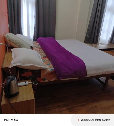 a bed with purple sheets and pillows on it at SALCHAN INN Home Stay in Takh