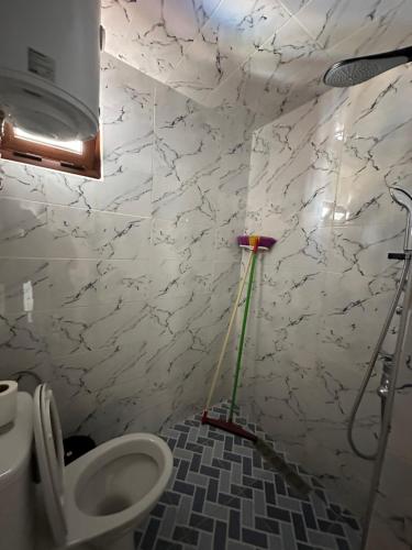 a bathroom with a toilet with a mop on the wall at Taghazout Hostel in Oulad Akkou