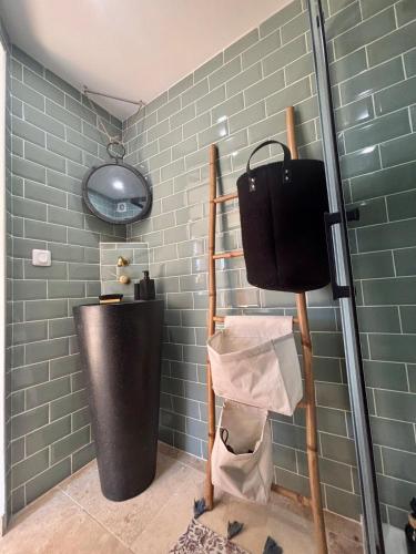 La salle de bains est pourvue d'un mur en carrelage vert et d'une étagère. dans l'établissement Studio ODEL - Charmant studio en pleine nature, à Trans-en-Provence