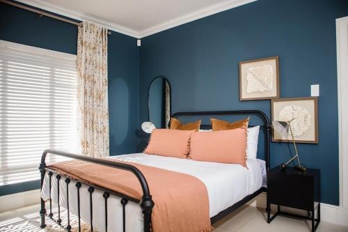 a bedroom with blue walls and a bed with orange pillows at 5 On Dana in Gqeberha