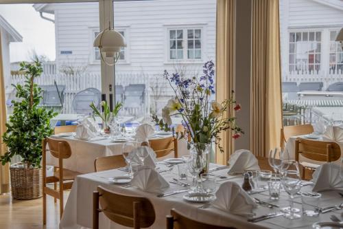 a dining room with tables and chairs with white tablecloths at Nevlunghavn Gjestgiveri in Nevlunghavn