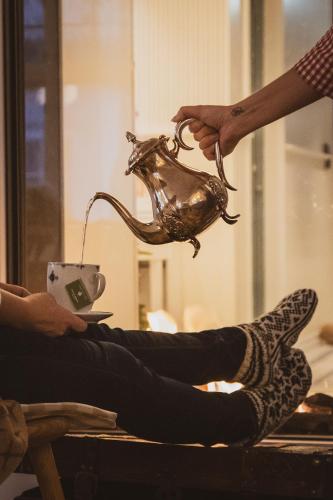 a person holding a tea pot and a person holding a cup at Nevlunghavn Gjestgiveri in Nevlunghavn