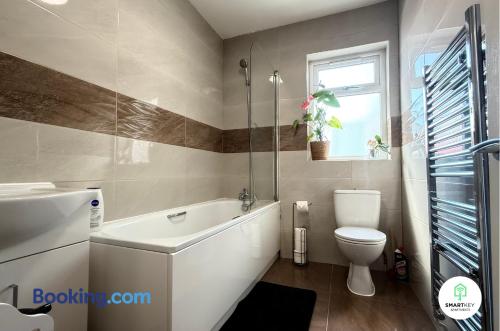 a bathroom with a tub and a toilet and a window at Ground Floor 1 Bedroom Apartment close to Woking train station in Woking