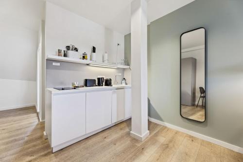 a white kitchen with a mirror and a counter at Limehome Bamberg Maximiliansplatz in Bamberg