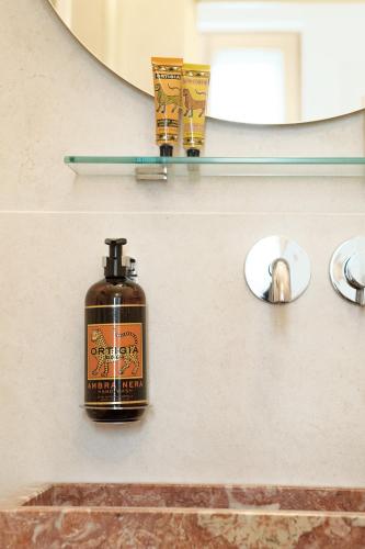 a bottle of soap on a bathroom sink in front of a mirror at Elysée Montmartre Hotel in Paris