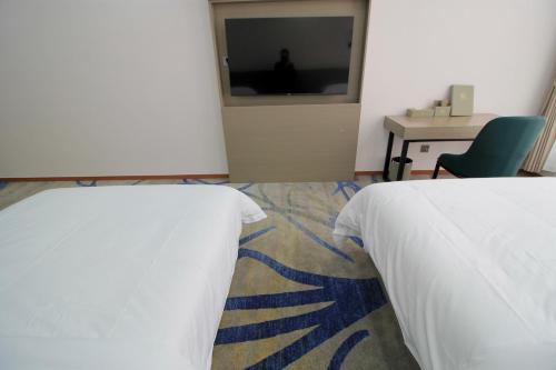 una habitación con dos camas y un escritorio y una silla en Carrey Hotel, en Lusaka