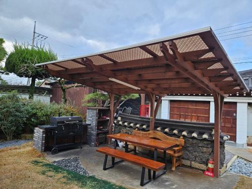 a wooden pavilion with a picnic table and a grill at Yeonriji in Gyeongju