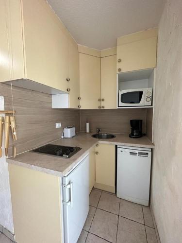 une petite cuisine avec un évier et un micro-ondes dans l'établissement Appartement face à la mer, à Canet