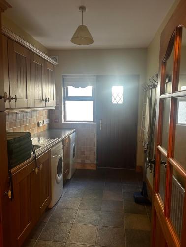 a kitchen with a washing machine and a window at Yewwood Cottage in Newry