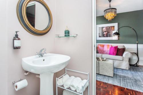 een badkamer met een wastafel, een spiegel en een bank bij St Martini Mountain View Studio in Kaapstad