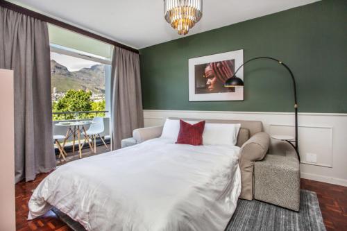 een slaapkamer met een bed, een stoel en een raam bij St Martini Mountain View Studio in Kaapstad