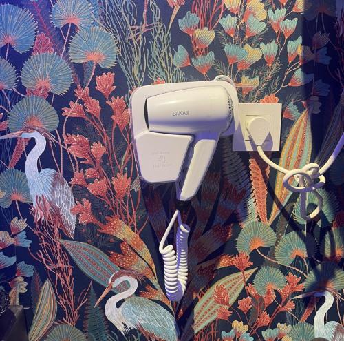 a hair dryer hanging on a wall with a wallpaper at Apartamentos de la Luz in Granada