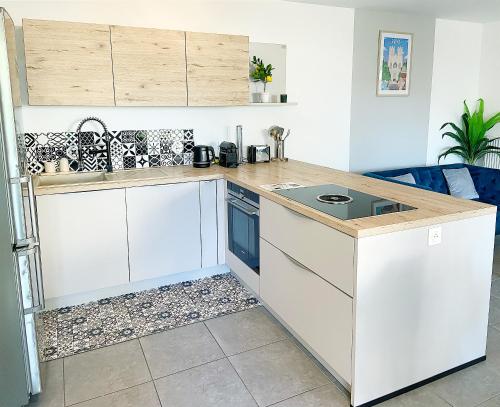 una cucina con mobili bianchi e un piano di lavoro di Chez Pablo, maison avec jardin et parking privé a Reims
