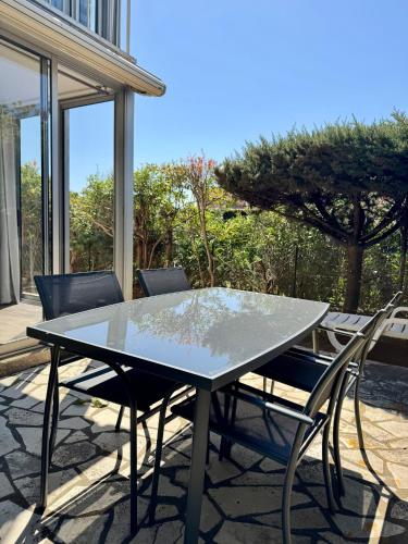 une table et des chaises en verre sur la terrasse dans l'établissement L'ocre du Sud - 6 pers - Histoire de clés, au Cap d'Agde