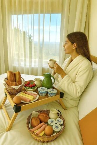 a woman sitting in bed with a tray of food at Cozy House in Rio de Janeiro
