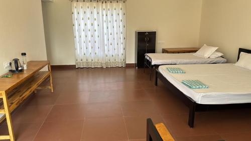 a room with three beds and a table and a window at Anantara Farmhouse Kitchen & Stay in Silāri