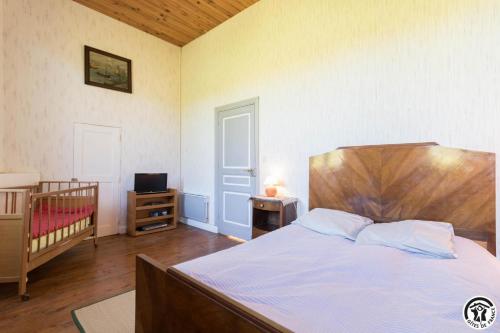 a bedroom with a bed and a crib and a television at Ancienne ecole in Montbrun-Bocage
