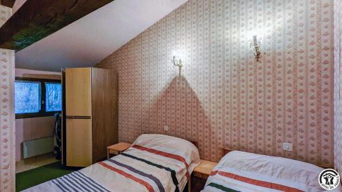 two beds in a room with pink wallpaper at L'ouastadet in Aspret-Sarrat