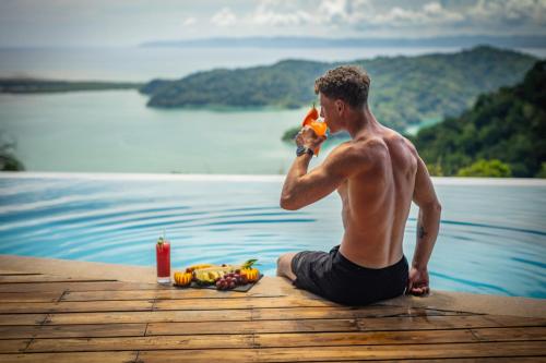 a man sitting on the edge of a dock eating fruit at Cielo Lodge in Golfito