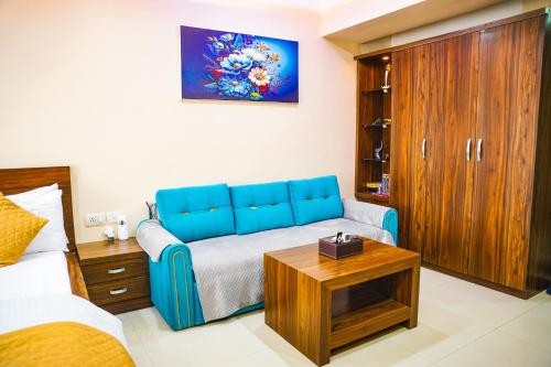a living room with a blue couch and a bed at Siddha Xanadu,New Town, kolkata Airport & CC2, One Room Apartment in kolkata