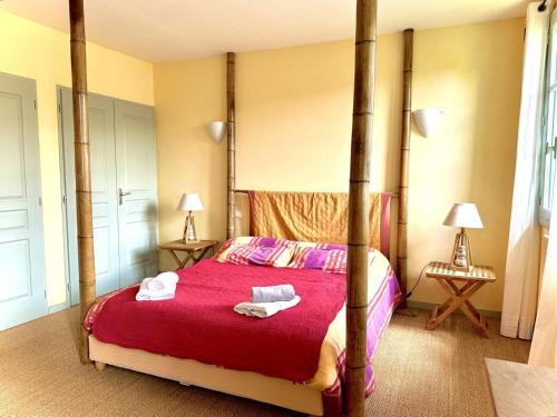 a bedroom with a four poster bed with towels on it at Le clos saint-paul - nature in Estadens