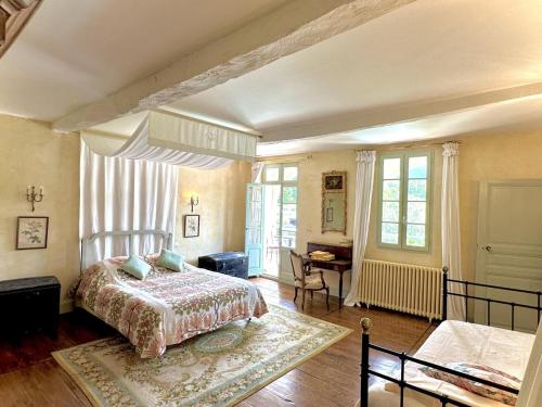 a bedroom with a bed and a desk and windows at Le clos saint-paul - comminges in Estadens