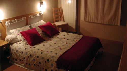 a bedroom with a large bed with red pillows at Baugnac in Lavalette