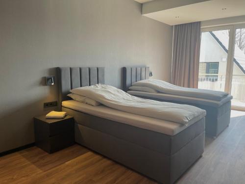 two twin beds in a room with a window at A & B Apartment und -Zimmervermietung in Tornesch